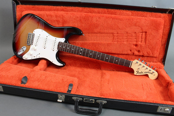 Fender Stratocaster electric guitar with sunburst finish in open black hard case with orange plush interior.