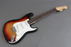 Fender Stratocaster electric guitar with sunburst finish, white pickguard, and rosewood fretboard on gray background