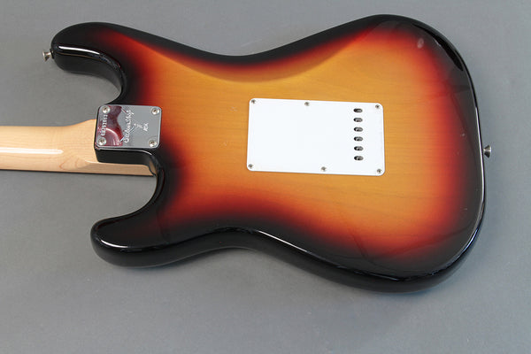 Back view of sunburst electric guitar body with maple neck and white tremolo cavity cover on gray background from Coffee House Guitars.