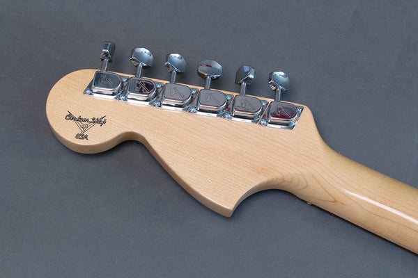 Close-up of maple neck headstock with chrome tuning pegs and Custom Shop USA logo on electric guitar against gray background