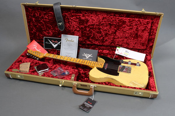 Fender vintage electric guitar with maple neck and black pickguard in open tweed hard case with red plush interior, including Fender certificates and accessories