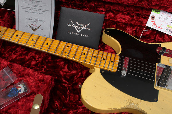 Close-up of Fender Custom Shop 1951 Telecaster Relic electric guitar body and neck in a red velvet case, showing worn vintage yellow finish, black pickguard, and Fender certificate of authenticity.