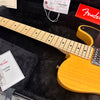 Close-up of Fender electric guitar maple neck and yellow body in black plush guitar case with Fender tags and guitar case manual