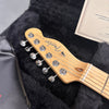 Close-up of Fender Telecaster maple headstock with chrome tuning pegs inside a black fur-lined guitar case with an instrument care card