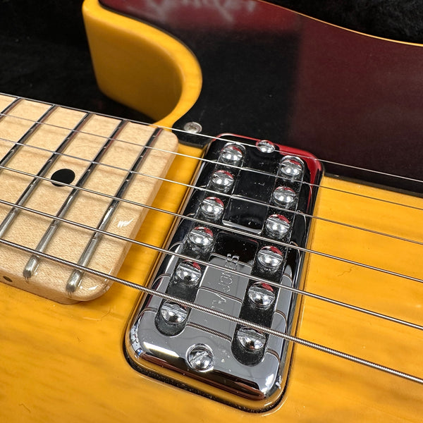 Close-up of chrome TV Jones pickup and strings on yellow electric guitar with maple fretboard