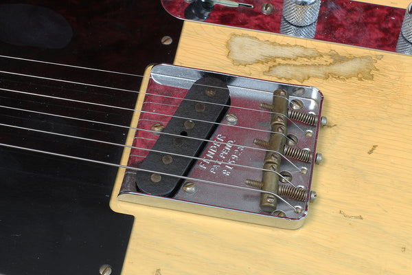 Close-up of vintage Fender Telecaster bridge plate with single-coil pickup and strings on aged natural wood finish guitar body