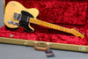 Vintage Fender Telecaster electric guitar with yellow finish and maple neck, displayed in open tweed hard case with red plush interior, featuring black pickguard and chrome hardware