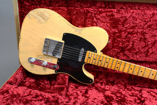 Vintage worn cream electric guitar with black pickguard and maple neck on red velvet guitar case lining