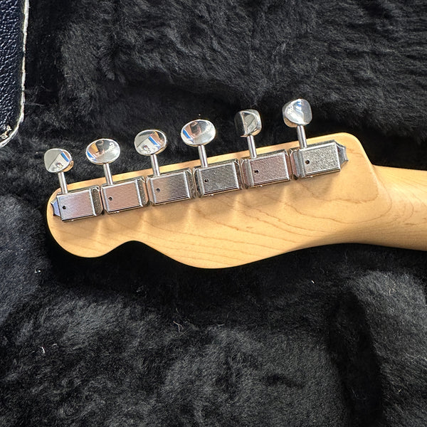 Close-up of chrome tuning pegs on the back of a maple guitar headstock resting in a black plush guitar case interior.
