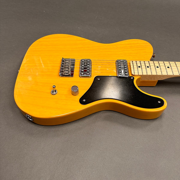Yellow electric guitar with maple neck and fretboard, black pickguard, dual humbucker pickups, single volume knob, and three-way toggle switch on gray background