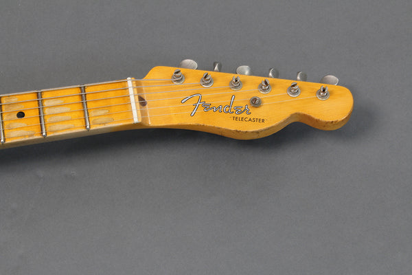 Close-up of vintage Fender Telecaster electric guitar headstock with tuning pegs and worn maple fingerboard against gray background