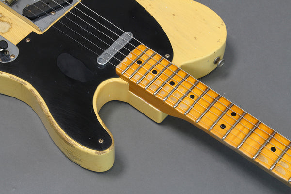 Close-up of vintage cream electric guitar body and maple fretboard with black pickguard and single-coil pickup showing wear and aging details