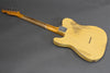 Vintage yellow relic electric guitar with maple neck and six tuning pegs, worn finish on back body and neck plate screws visible on gray background