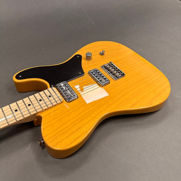 Electric guitar with honey blonde finish, black pickguard, maple neck, and dual chrome pickups on gray background