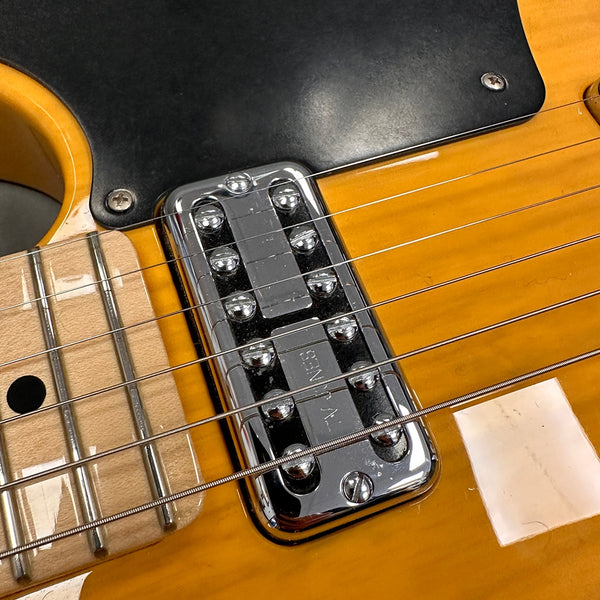 Close-up of vintage chrome guitar pickup on yellow electric guitar body with maple fretboard and black pickguard.