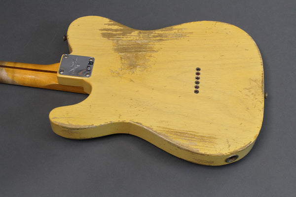 Back of vintage yellow electric guitar with worn finish and string ferrules on gray background
