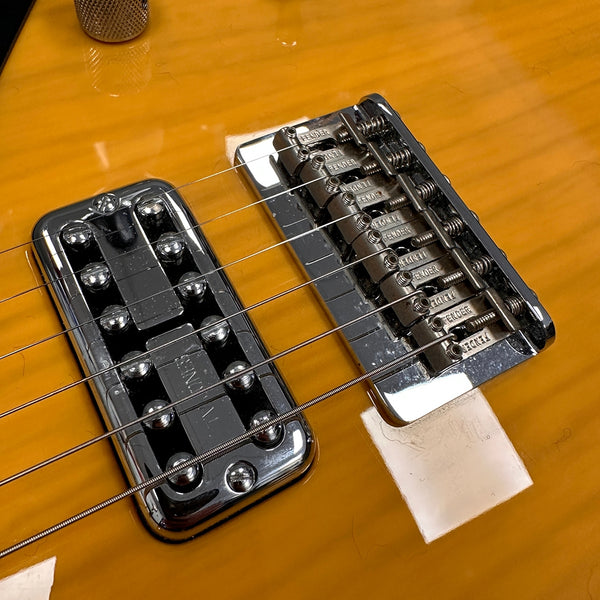Close-up of electric guitar bridge and chrome mini humbucker pickup on honey burst finish guitar body with Fender-branded saddles and hardware