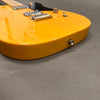 Close-up of honey blonde electric guitar body with chrome bridge and pickup on gray fabric background