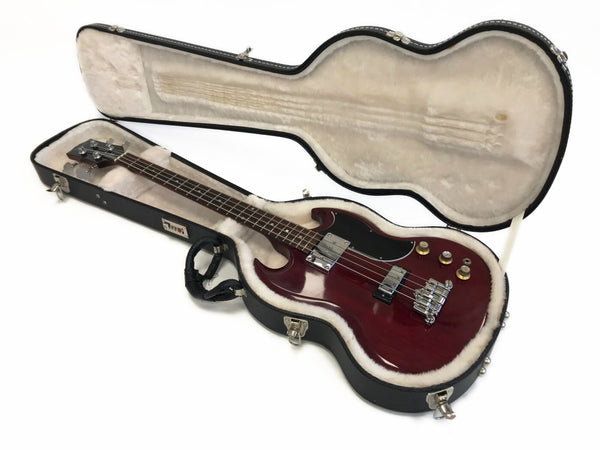 Electric bass guitar with cherry red finish in cushioned black hard case with plush interior and cable inside