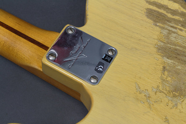 Close-up of Fender Custom Shop metal neck plate on vintage worn cream electric guitar body with three-tone maple neck and skunk stripe detail