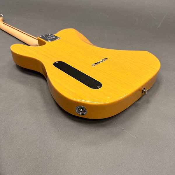 Honey blonde electric guitar body with six string ferrules, black backplate, and chrome input jack on gray background