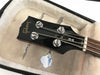 Close-up of black Gibson SG bass guitar headstock with chrome tuning pegs inside plush lined hard case