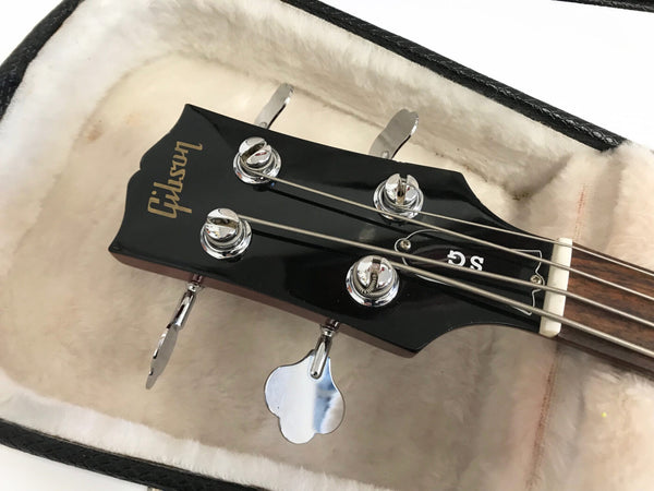 Close-up of black Gibson SG bass guitar headstock with chrome tuning pegs inside plush lined hard case