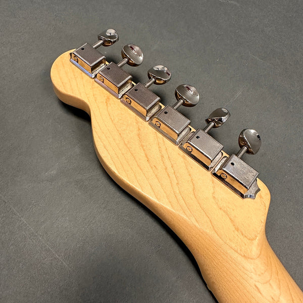 Close-up of maple guitar neck headstock with six chrome tuning pegs on dark gray background