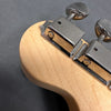 Close-up of chrome tuning pegs and natural wood guitar headstock on dark background