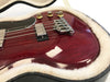 Close-up image of cherry red electric bass guitar body with chrome bridge and pickups in plush-lined guitar case.