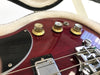 Close-up of volume knobs and bridge on red electric guitar in plush-lined guitar case