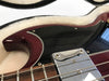 Close-up of cherry red electric guitar body with black pickguard and chrome pickup in guitar case with plush white lining