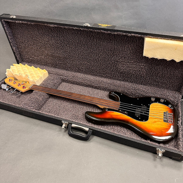 Fretless electric bass guitar with sunburst finish and black pickguard in open plush-lined hard case with egg crate foam head support