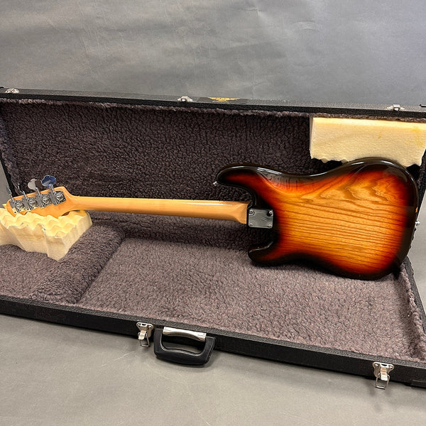 Sunburst electric bass guitar back view with maple neck inside black hard shell case with plush interior lining