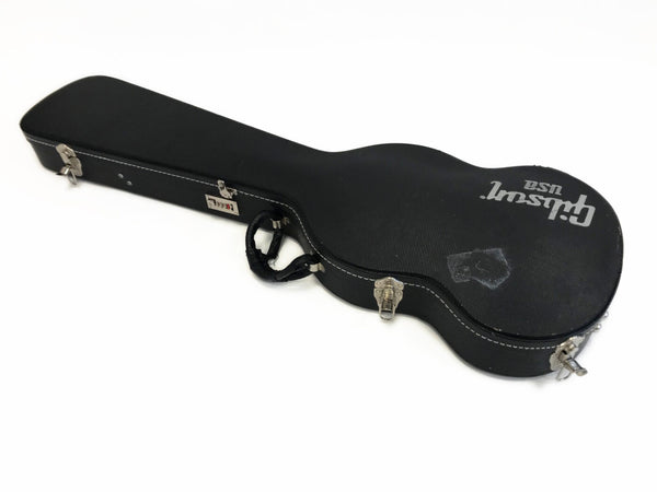 Black hard shell Gibson USA guitar case with metal latches and padded handle on white background