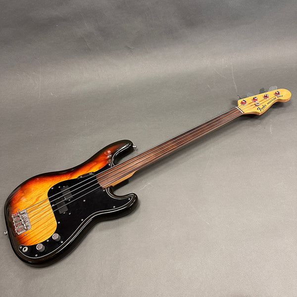 Fender Precision Bass electric bass guitar with sunburst finish and fretless rosewood neck on gray background