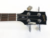 Close-up of Gibson SG bass guitar headstock with black finish, chrome tuning pegs, and rosewood fretboard on white background