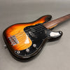 Sunburst electric bass guitar with black pickguard and four strings on gray surface