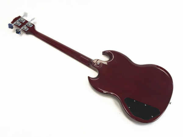 Back view of cherry red electric bass guitar with four tuning pegs and black control cavity cover isolated on white background