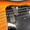 Close-up of electric bass guitar strings and EMG pickups on a natural wood finish body with black pickguard and metal screws