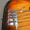 Close-up of vintage electric bass guitar bridge with four metal strings and sunburst finish body