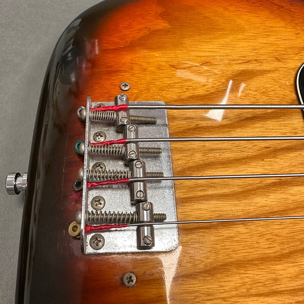 Close-up of vintage electric bass guitar bridge with four metal strings and sunburst finish body