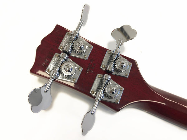 Close-up of the back of a bass guitar headstock with Grover tuning pegs and dark wood finish, showing chrome machine heads and gears.
