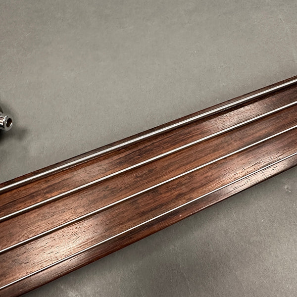 Close-up of guitar fretboard with metal strings and polished wooden surface on neutral background