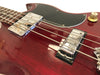 Close-up of red electric guitar body showing chrome pickups, black pickguard, and volume knob with strings in focus