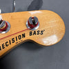 Close-up of natural wood Precision Bass guitar headstock with chrome tuning pegs and red string winding, made in USA text visible