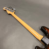 Back view of Fender electric bass guitar showing maple neck and tuning pegs on gray background