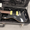 Black electric guitar with cream P90 pickups and rosewood fretboard in open black plush-lined hard case on gray surface