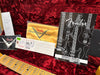 Fender Custom Shop guitar case interior with Fender owner's manual, custom shop yellow polishing cloth, authenticity cards, and guitar neck on red plush lining