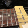 Close-up of electric guitar rosewood fretboard with mother-of-pearl inlays and vintage-style cream pickup with metal screws and steel strings.